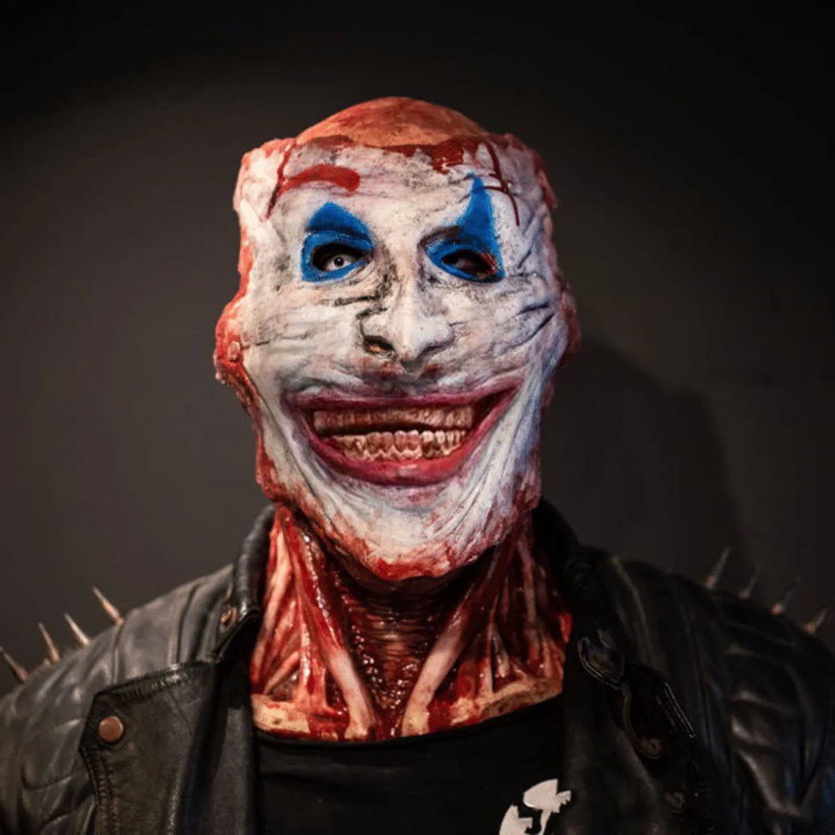 Clown-style outer mask worn with a dark jacket