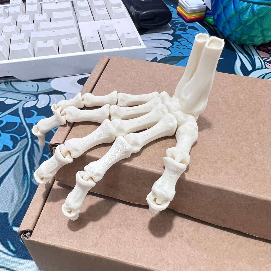 Miniature skeleton hand on a box beside a keyboard