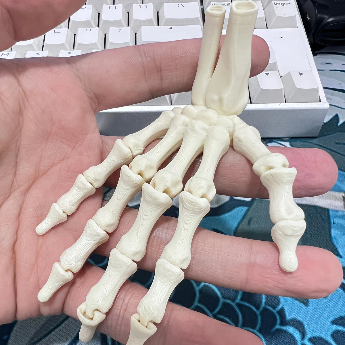 Skeleton hand ornament shown in a palm for scale